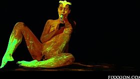 The glow in the dark goddess fingers her shaved pussy with a dildo.