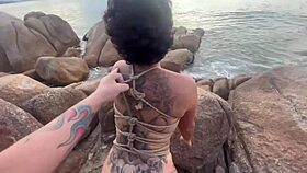 Shibari bondage performed in public with small tits exposed.
