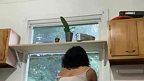 Latina milf enjoys washing dishes in the kitchen with a smile.