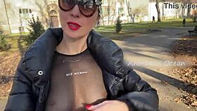 A beautiful woman shows her large breasts while she is walking in a public park