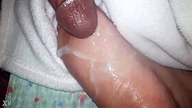 A close-up of oiled feet receiving a warm liquid splash.