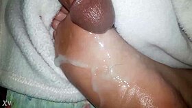 A close-up of oiled feet receiving a warm liquid splash.